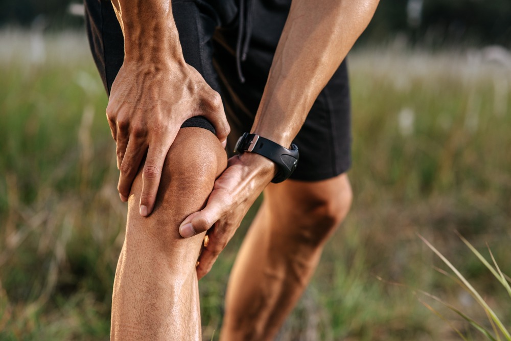 Athlete experiencing knee pain while holding their knee, illustrating the need for effective treatment options for active individuals with knee injuries.